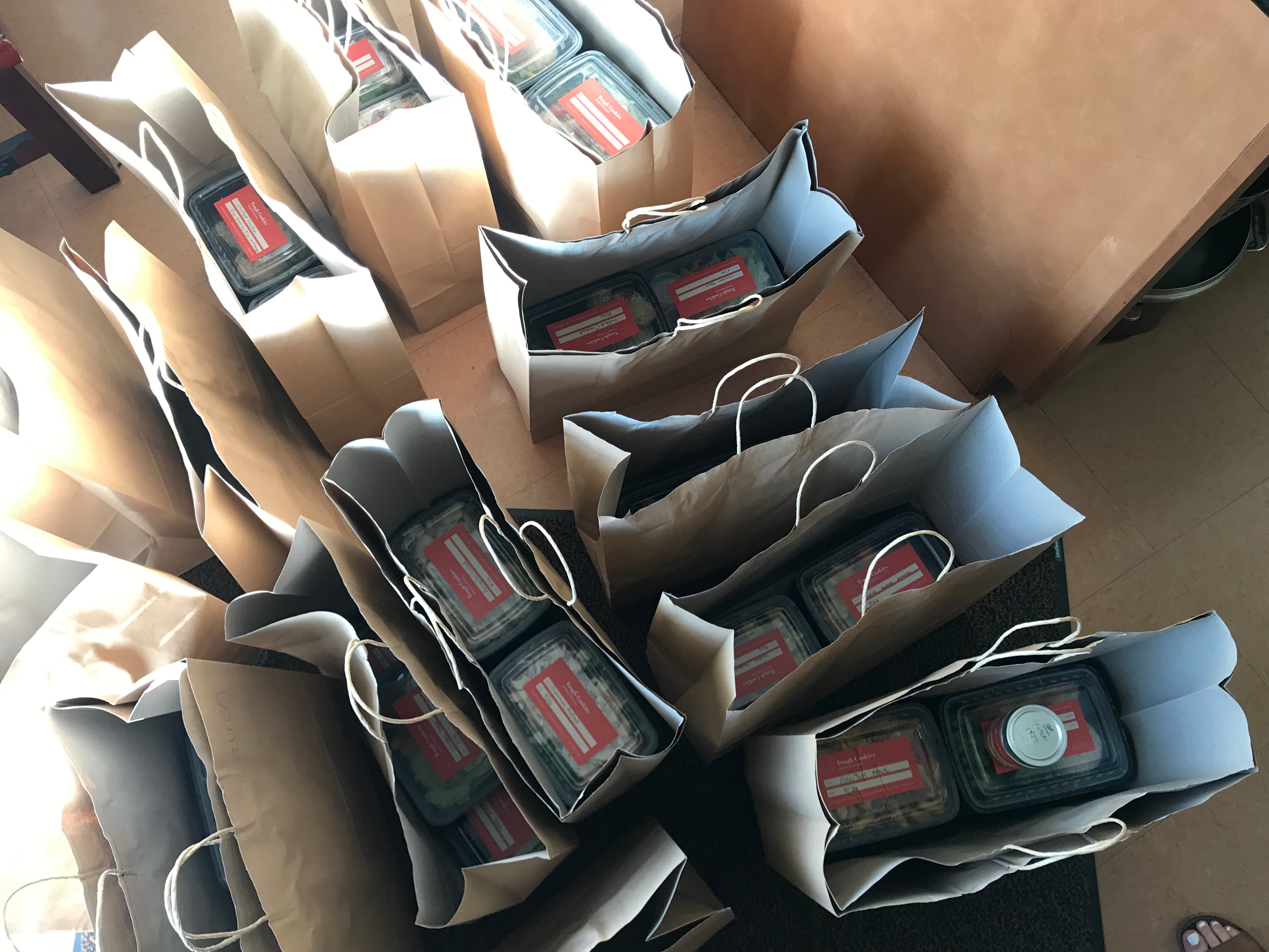 Paper bags holding Tough Cookies meals with the original orange labels during the first months
